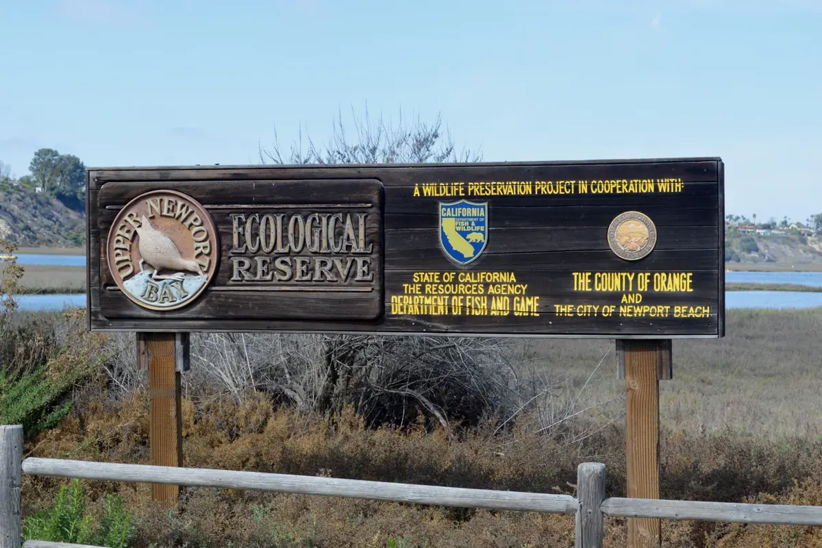 The Upper Newport Bay Ecological Reserve boundary sign, with the marsh and open water behind it, Newport Beach CA