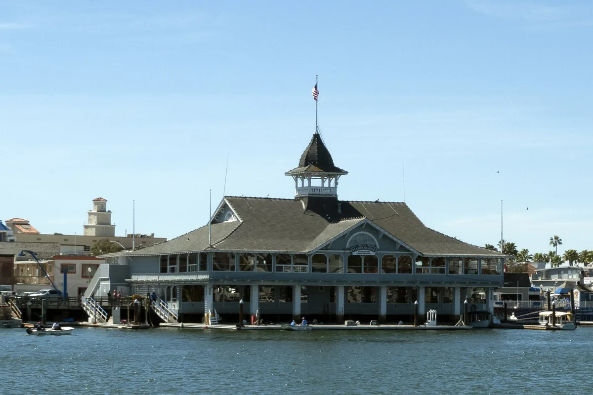 The Balboa Pavilion lit at dusk with moored boats in Newport Harbor, Balboa Peninsula, Newport Beach CA