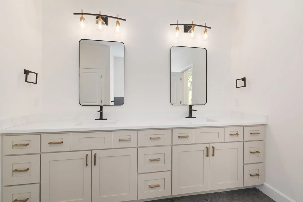 A double bathroom vanity with shaker fronts, two mirrors and brass pulls in a Newport Beach CA home