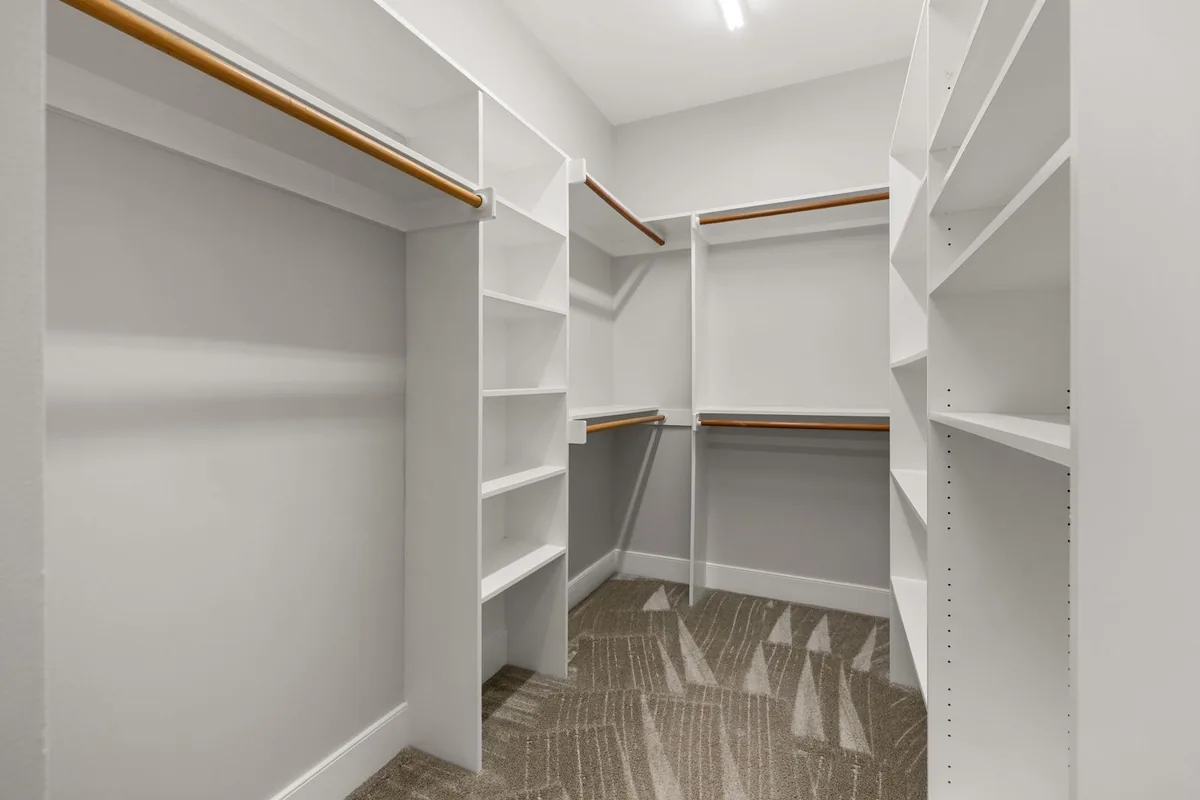 An empty white fitted walk-in closet with adjustable shelving and hanging rods in a Newport Beach CA home