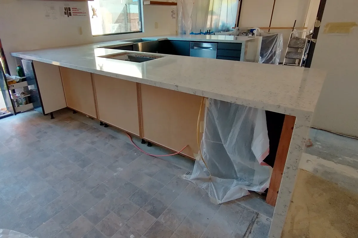 A quartz countertop newly set on unfinished cabinet boxes mid-install in a Newport Beach CA kitchen