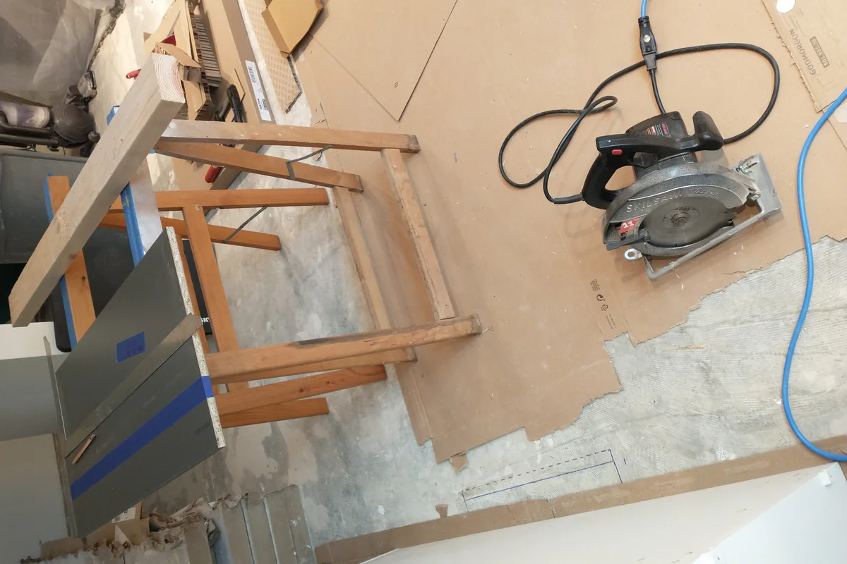 A circular saw and sawhorse on a protected floor during a cabinet installation in a Newport Beach CA kitchen