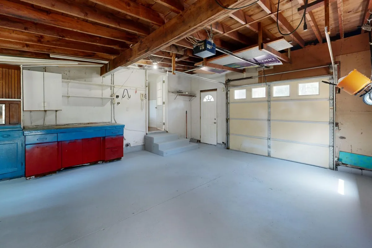 A garage with wall-mounted and base storage cabinets beneath exposed joists in a Newport Beach CA home