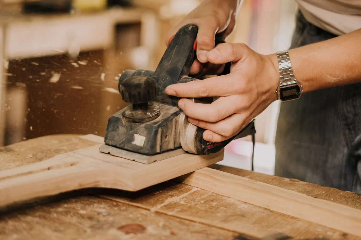 A power planer taking a shaving off a board in a workshop near Newport Beach CA
