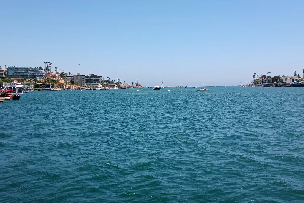 Newport Harbor entrance with waterfront homes and moored boats, Newport Beach CA