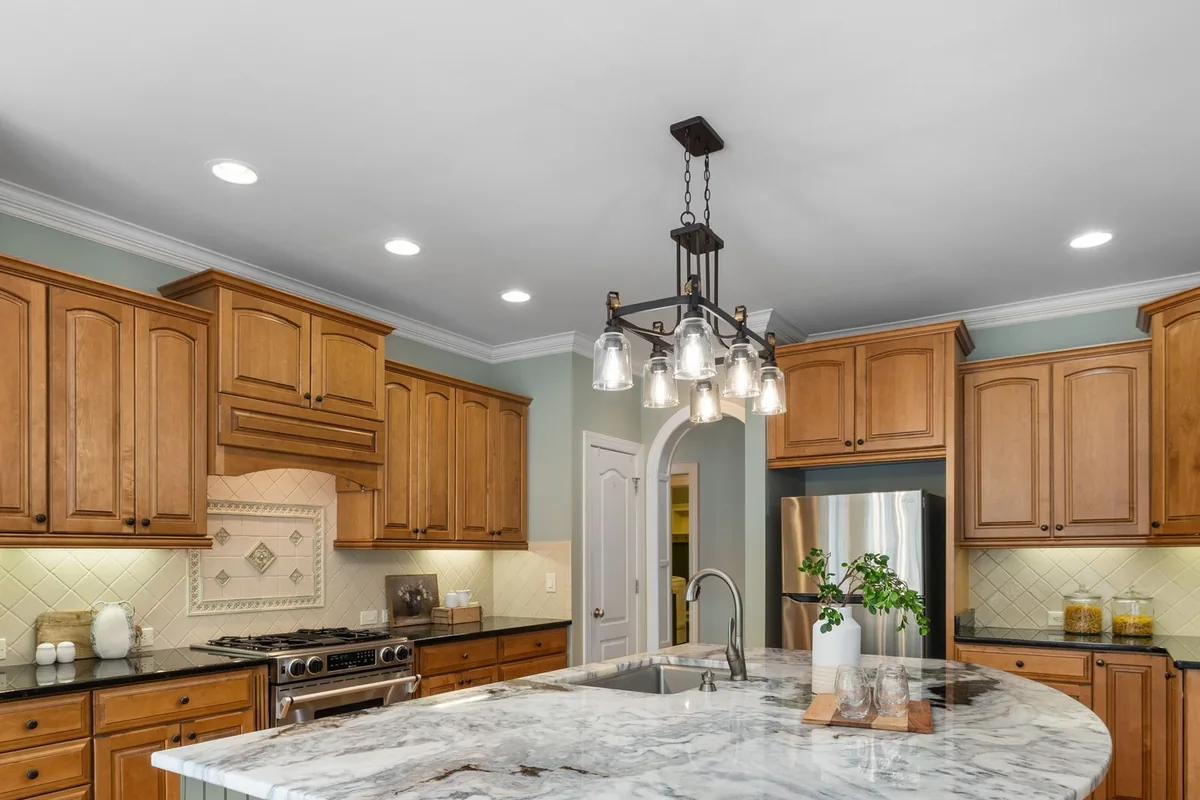 A curved marble-topped kitchen island with raised panel cabinets in a Newport Beach CA home