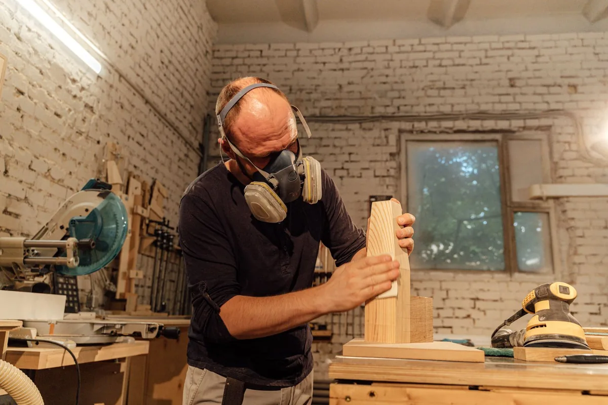 Cabinet doors being sanded back during a refinishing job, with respirator and dust extraction