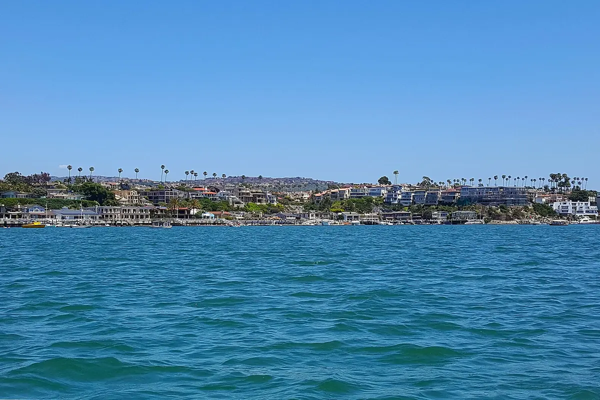 Houses and moored boats along a West Newport harbour channel in Newport Beach CA