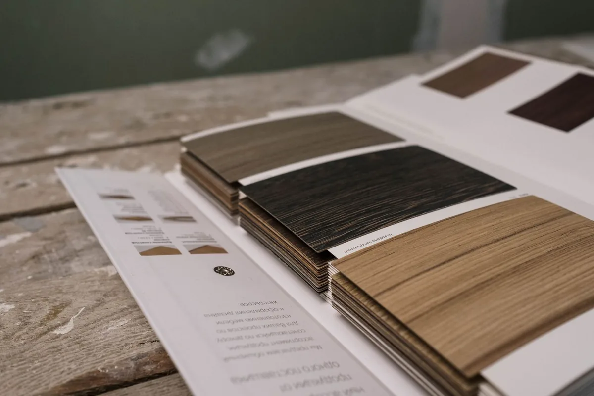 A veneer sample book open on a workbench showing light and dark cabinet wood samples, Newport Beach CA
